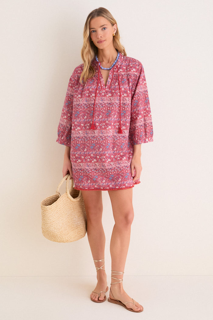 Woman in classic Americana Batik Stripe Bondi Coverup, featuring effortless floral print, tassel ties, and fringed hem. Styled with fun accessories for a high-end beach look.