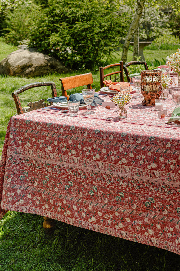 A summer table set with a red tablecloth and colorful napkins.
