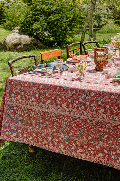 A summer table set with a red tablecloth and colorful napkins.