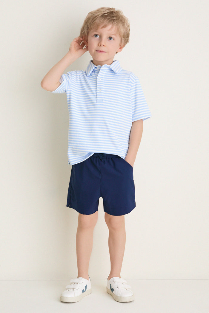 Young boy wearing the classic Bachelor's Blue and White Le Club Polo with navy shorts and white sneakers, embodying an effortless, fun, and high-end style.