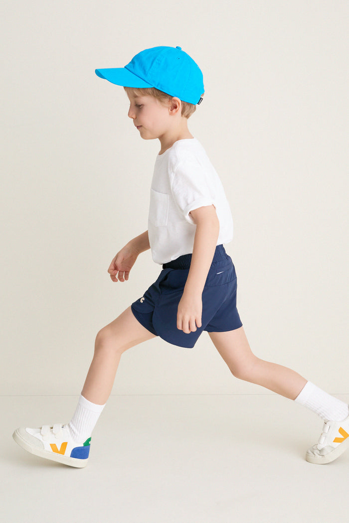 Young boy in profile wearing the classic Before Sunrise Blue Cardio Short, showcasing effortless style and high-end athletic functionality. Perfect balance of fun and practicality.