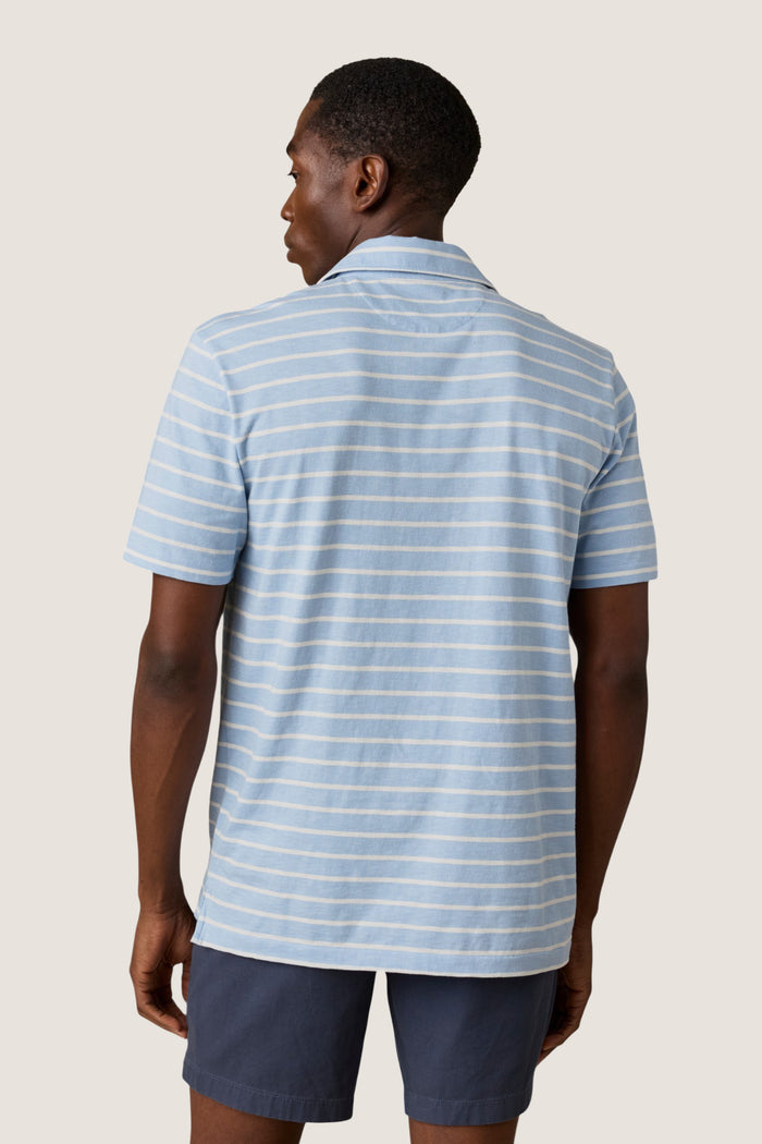 Person wearing the classic Bermuda Sail Stripe Sunwashed Tee Shirt Polo with thin stripes, exuding an effortless, high-end style against a neutral background, embodying Tuckernuck's fun shopping experience.