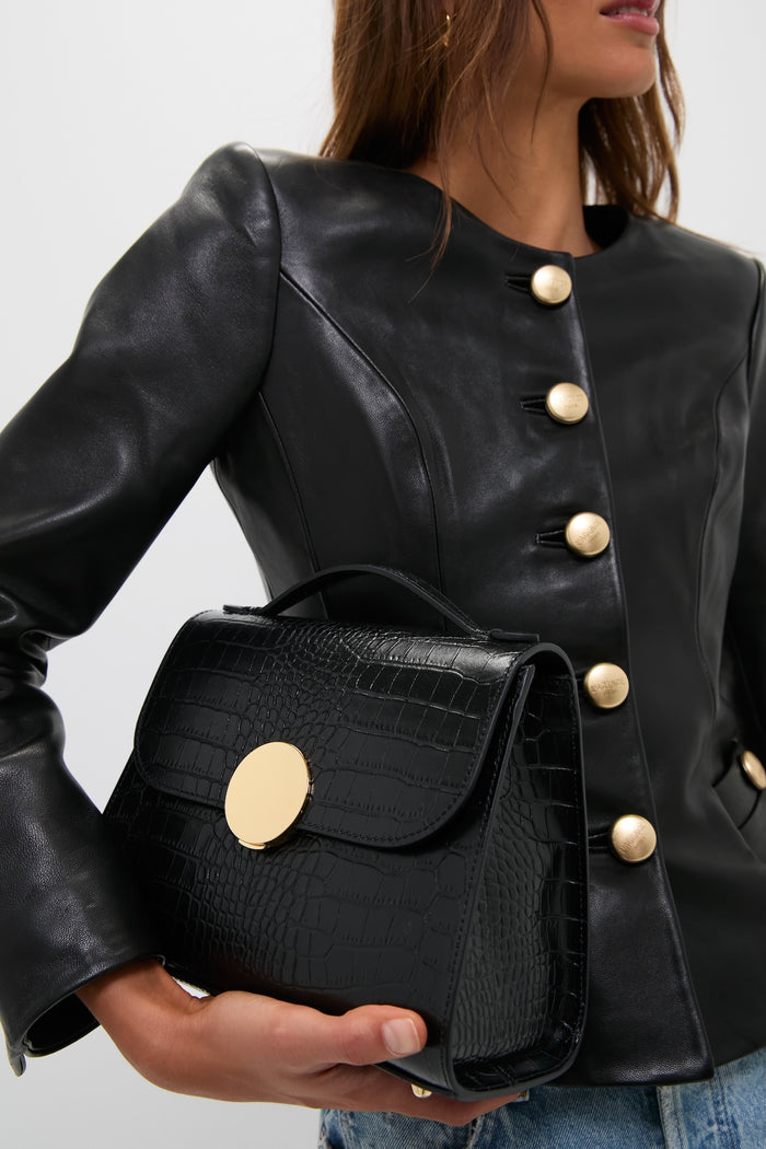 Woman modeling Black Bombo Croco Top Handle Satchel Bag, a classic, high-end accessory with a crocodile-embossed leather design, goldtone hardware, exuding effortless style and sophistication.