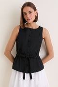 Young woman wearing a classic, high-end Black Cotton Poplin Francoise Top with a high neckline, sleeveless design, and cinched waist, embodying effortless sophistication and fun style.