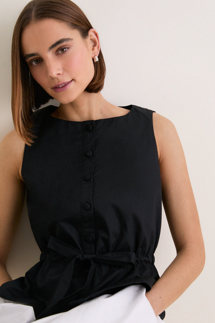 Young woman in a Black Cotton Poplin Francoise Top with high neckline and cinched waist, exuding classic, effortless elegance for a fun, high-end look.