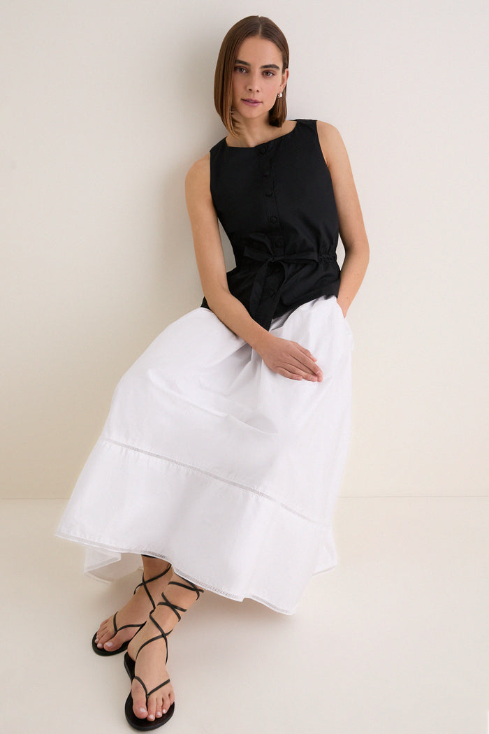 Young woman in a classic, high-end Black Cotton Poplin Francoise Top with high neckline and self-tie waist, embodying effortless and fun sophistication.