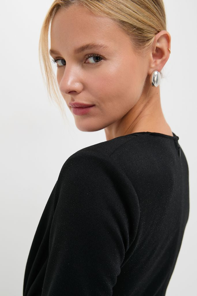 Young woman showcasing the Black Jersey Knit Wilbanks Midi Dress with structured shoulder pads and elegant twist detail, embodying a classic, effortless, and high-end style.