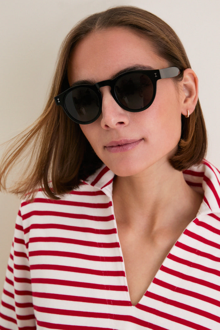 Young woman wearing classic Black Leonard Sunglasses by Illesteva, round silhouette and chic style, embodying an effortless, high-end look with fun, everyday versatility.