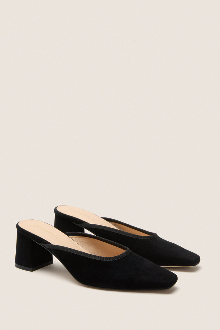 Black Suede Tilda Mules, classic and effortlessly chic, feature an elongated square toe, block heel, and mule silhouette, embodying high-end craftsmanship for versatile, fun styling.