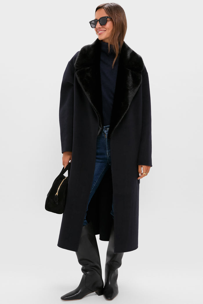 Woman wearing classic black overcoat with plush lapel, dark jeans, knee-high boots, effortlessly styled with a small handbag and sunglasses. Embodying high-end, fun sophistication.