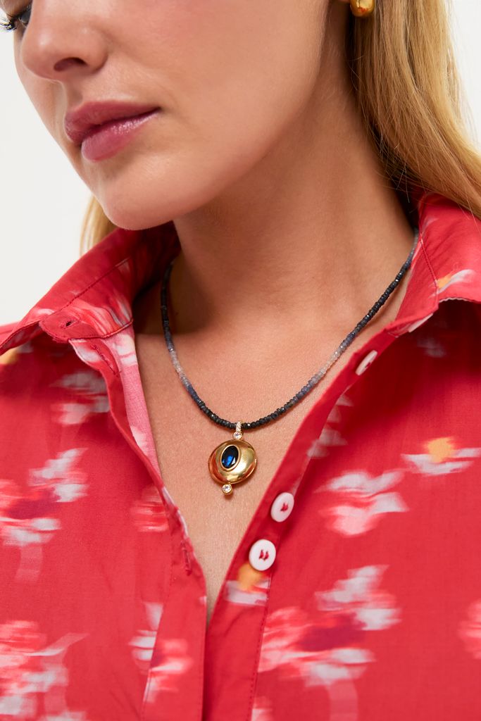 Close-up of a woman's neck wearing the Blue Orion Necklace, featuring an oval blue gemstone and tiny diamond accents, exuding a classic, effortless, and high-end style.