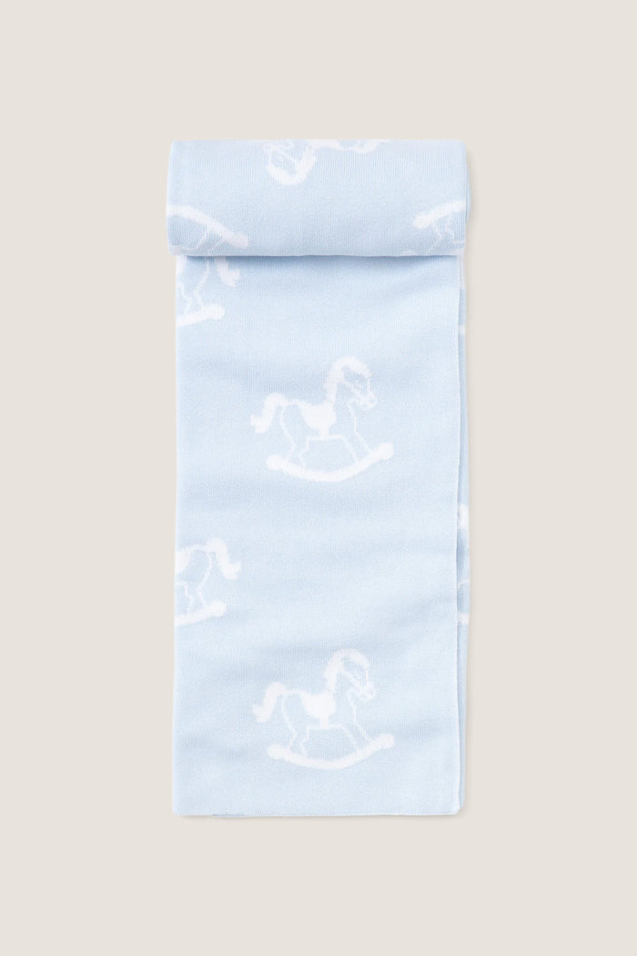 Blue Rocker Knit Blanket, a classic, ultra-soft cotton blanket featuring a playful white rocking-horse pattern on pale blue, perfect for effortless, high-end snuggling with your little one.
