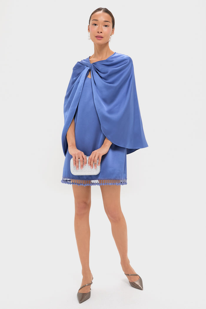Model in a classic Blue Satin Mountbatten Cape over a mini dress, holding a clutch, exuding effortless elegance with fun, high-end accessories.