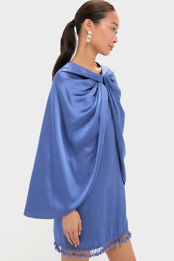 Model in profile showcasing the Blue Satin Mountbatten Cape, effortlessly draped over a matching mini dress with tassel hem, exuding classic, high-end style perfect for fun, festive occasions.