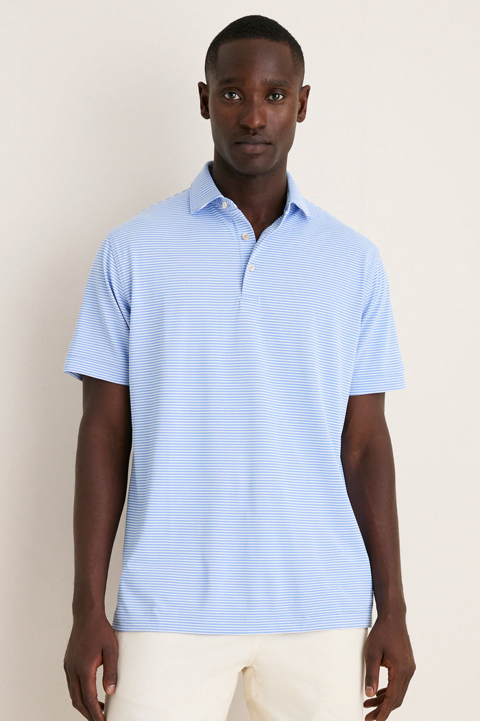 Man wearing the Bluebird Grace Performance Mesh Polo, a classic, effortless, high-end shirt with subtle stripes, paired with cream pants, embodying fun sophistication for versatile occasions.