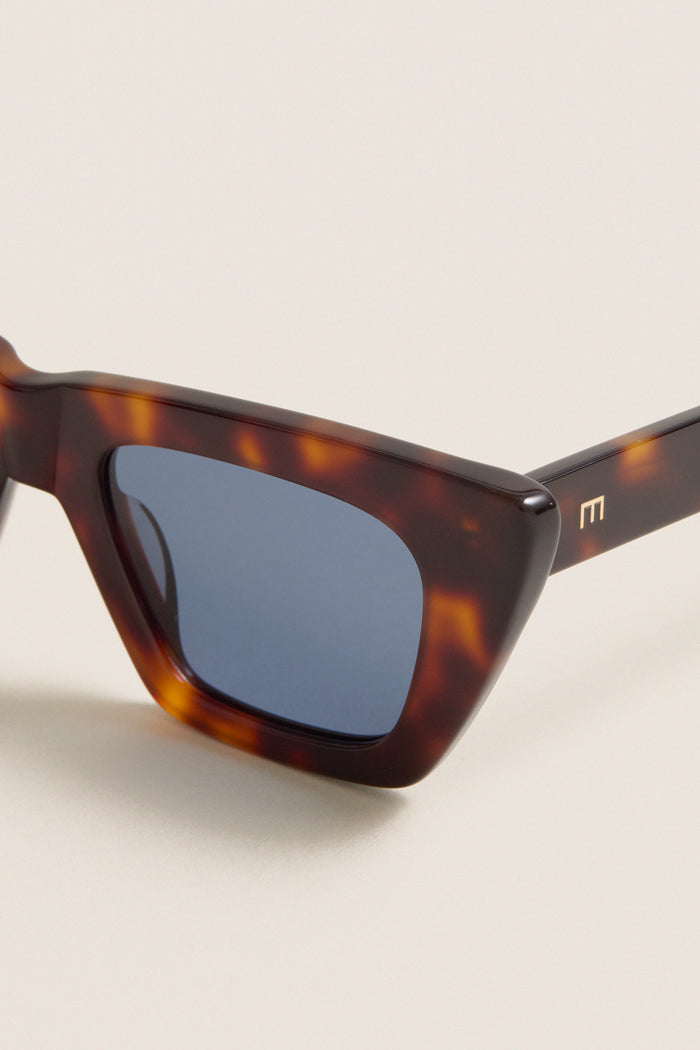 Brown Tortoise Dark Blue Lens Lori Sunglasses exude a classic, effortless charm with their chic cat-eye design, featuring high-end tortoiseshell frames and gold-tone M logo detail.