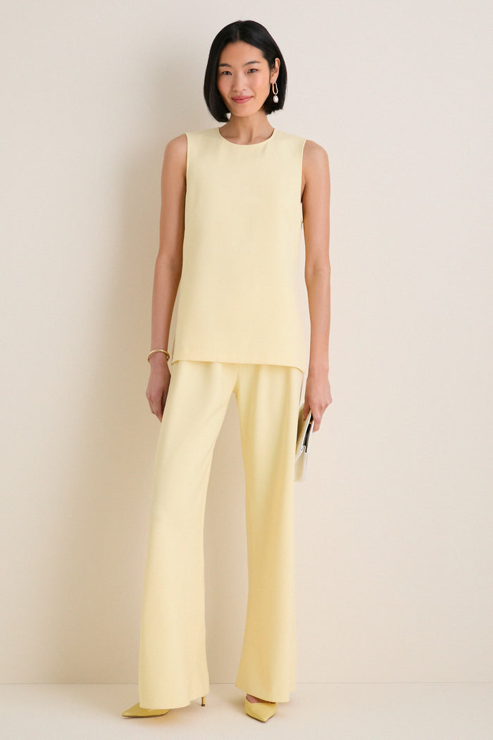 Woman models the Butter Maxime Top, a classic sleeveless tunic with side slits, epitomizing effortless, high-end style, paired with matching trousers and pointed heels.