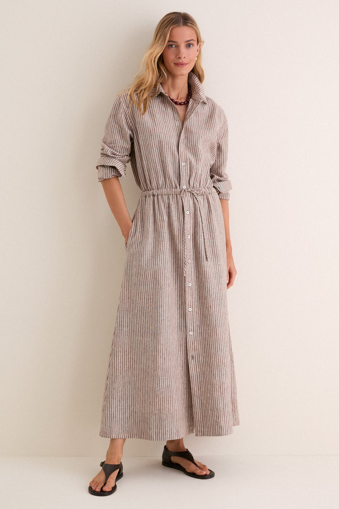 Woman wearing the Cafe Stripe Linen Julien Shirt Dress, a classic, high-end piece with effortless style featuring a drawstring waist and rolled sleeves, accessorized for a fun, relaxed look.