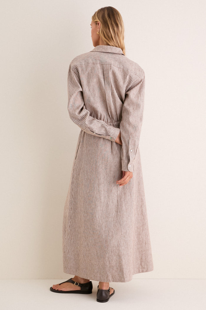 Woman wearing the classic Cafe Stripe Linen Julien Shirt Dress with a cinched waist and buttoned cuffs, paired effortlessly with black leather sandals for a high-end, fun look.