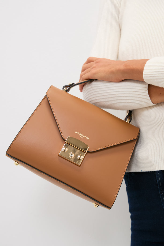 Caramel Peggy Top Handle Satchel Bag—classic, high-end leather with gold hardware—captures an effortless style, perfect for any fun, confident outing.