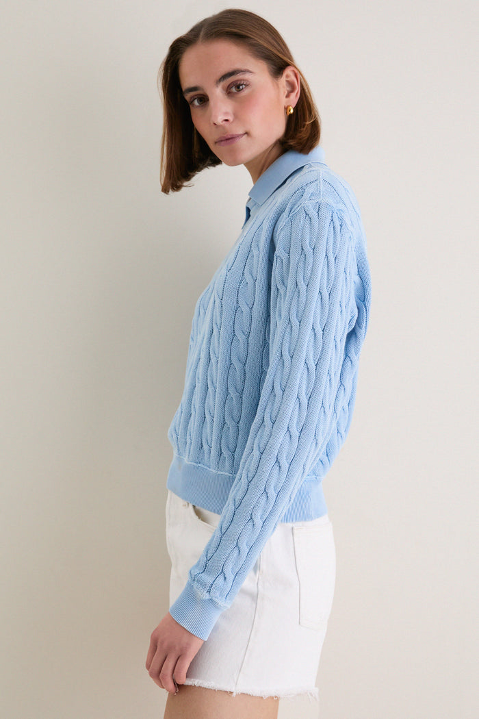 Young woman in profile wearing Polo Ralph Lauren's Chambray Blue Cotton Knit Polo, showcasing its classic cable-knit design and effortless, high-end style with a vintage-inspired finish.