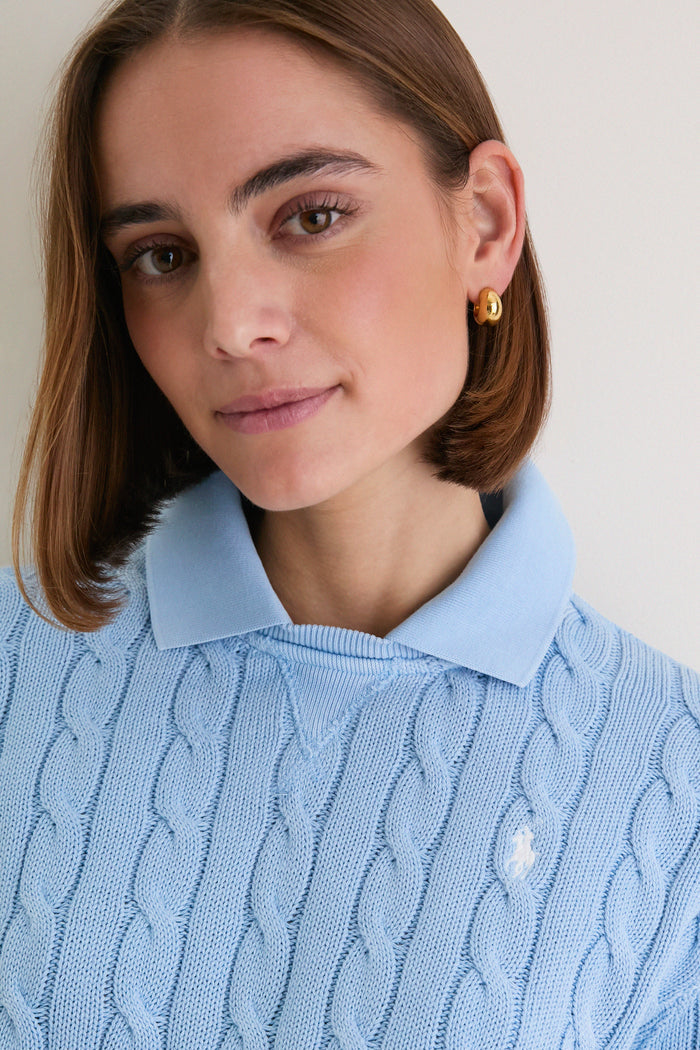 Young woman in a Chambray Blue Cotton Knit Polo by Ralph Lauren, featuring a classic cable-knit design and embroidered pony logo, exuding effortless, high-end style.