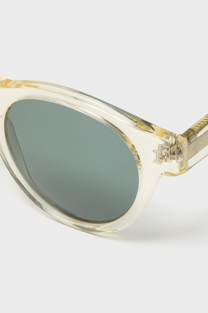 Champagne Leonard Sunglasses with translucent yellow acetate frame and round green-tinted lenses; classic, effortless design featuring metal hinge, handmade in Italy for a fun, high-end look.