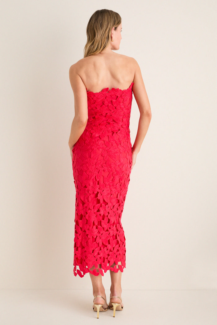 Woman in classic Cherry Red Philomena Midi Dress, strapless with floral crochet and scalloped hem, paired with nude high-heeled sandals, exuding effortless, high-end style.