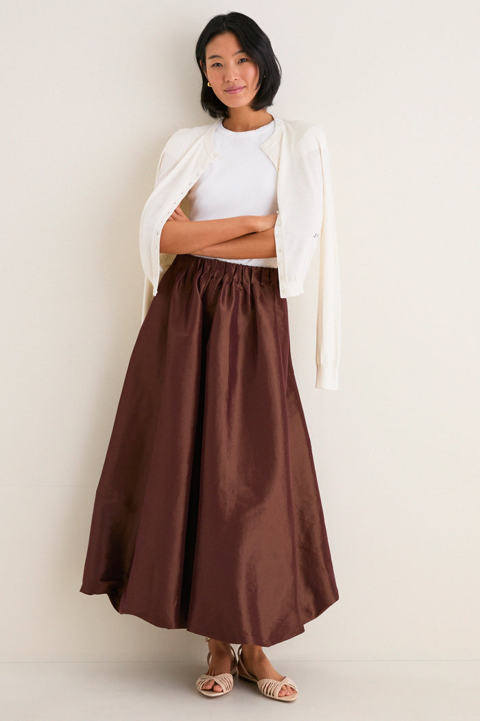 Young woman in a classic, effortless style wearing the Chestnut Taffeta Cynthia Bubble Skirt with its flirty bubble hem and elastic waistband, showcasing high-end, fun elegance.