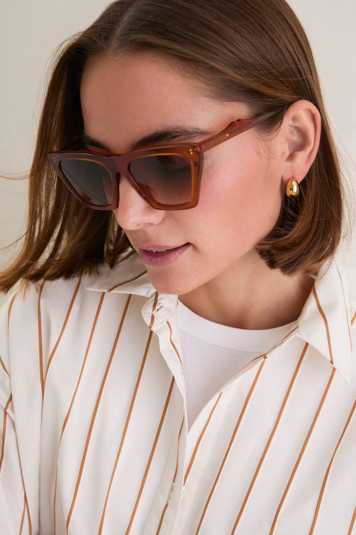 Woman models Cider Lisbon Sunglasses, showcasing a classic cat-eye design with a chic, high-end flair. These oversized frames offer an effortless, fun style, perfect for everyday wear.