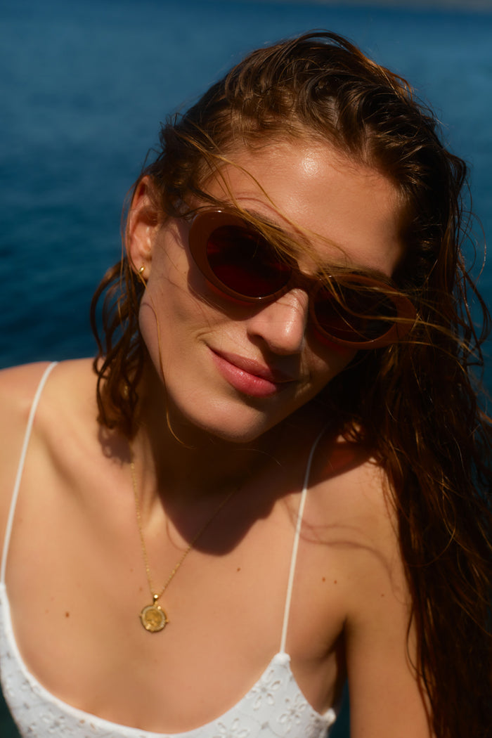 Woman in sunglasses in a white one piece swimsuit.
