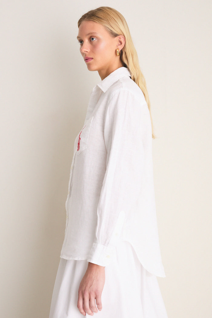 Classic Oxford White Linen Button Down modeled side-profile, showcasing relaxed fit, point collar, shell buttons, and embroidered detail on chest pocket for an effortless, high-end style.