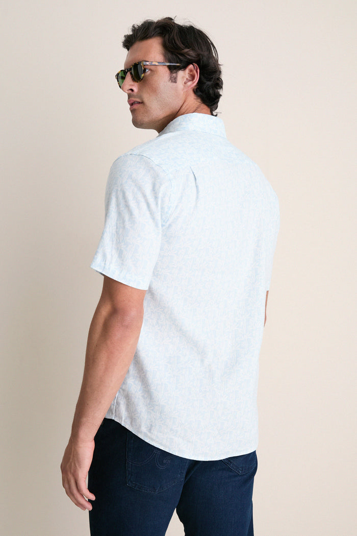 Man in a classic, effortless Clear Sky Leaf Breeze Shirt with subtle leaf print, styled with dark jeans and tortoiseshell sunglasses, embodying high-end, fun summer fashion.