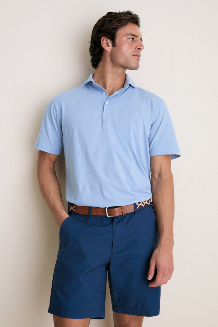 Man wearing Cloudy Blue Ryles Crown Flex Cotton Polo with cutaway collar, classic fit, short sleeves, tucked into dark shorts, embodies an effortless, high-end style.