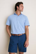 Man wearing Cloudy Blue Ryles Crown Flex Cotton Polo with cutaway collar, classic fit, short sleeves, tucked into dark shorts, embodies an effortless, high-end style.