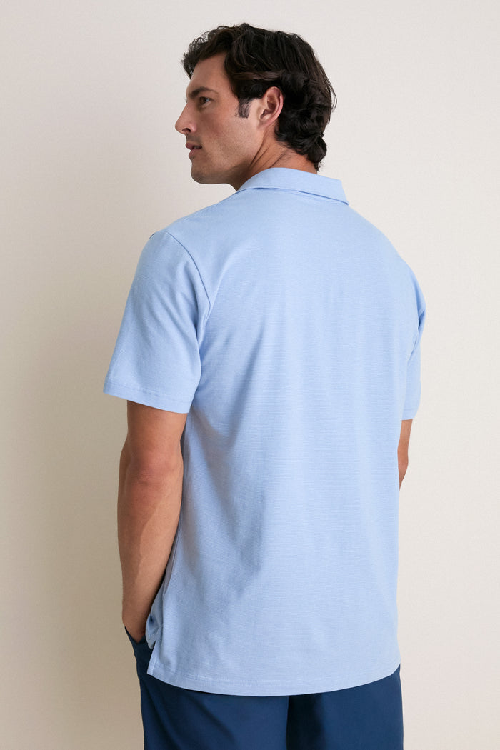 Man in light blue Cloudy Blue Ryles Crown Flex Cotton Polo with classic cutaway collar and dark blue bottoms, exuding effortless, high-end style.