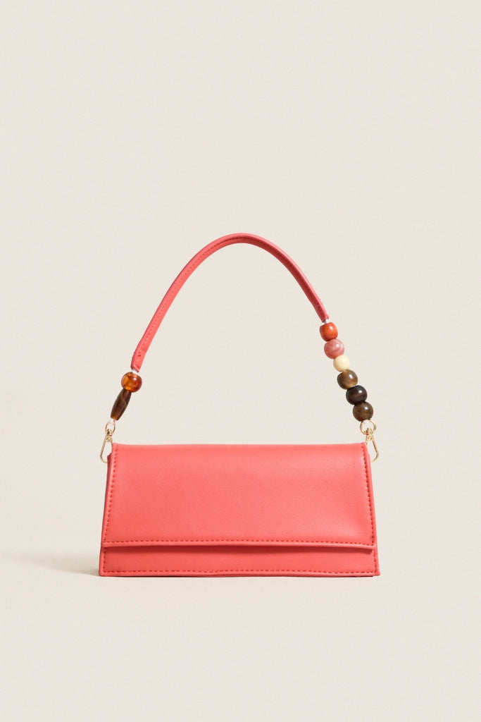 Coral Brooks Crossbody: A classic, fun mini purse in coral-red with a structured design, featuring an effortless sculpted beaded handle for a high-end, modern look.