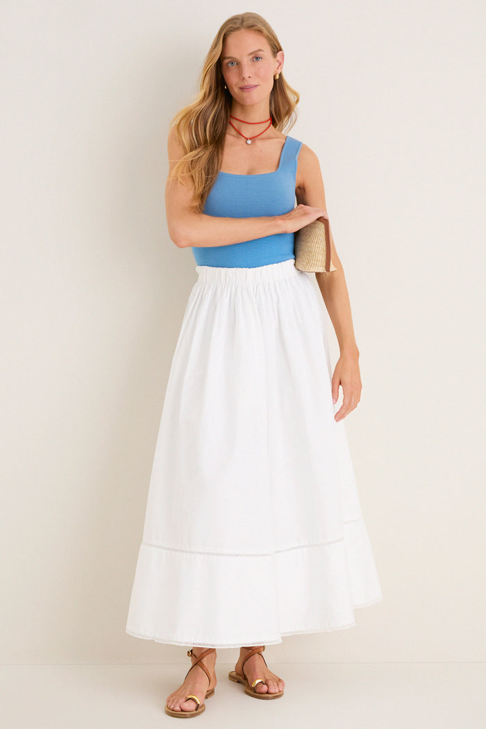 Woman in a classic, effortless outfit highlights the Coral Red Necklace Cord with Blue Bezel Charm, showcasing its fun, high-end versatility and vibrant style.