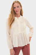 Young woman in a Cowrie Adriel Blouse: semi-sheer with pintucks, ruffled trim, peplum hem, creating a classic, effortless, high-end look, paired with straight-leg trousers.