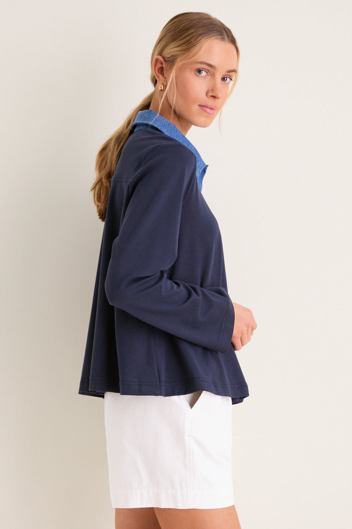 Young woman models the classic, high-end Denim Collar Carlyn Long Sleeve Polo, showcasing its effortless style with playful denim accents and a fun, relaxed fit.