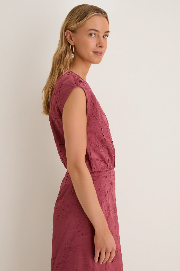 Young woman in a crinkled-texture Fig Gisella Top, showcasing a classic, effortless style with sculptural earrings for a high-end, fun fashion look.