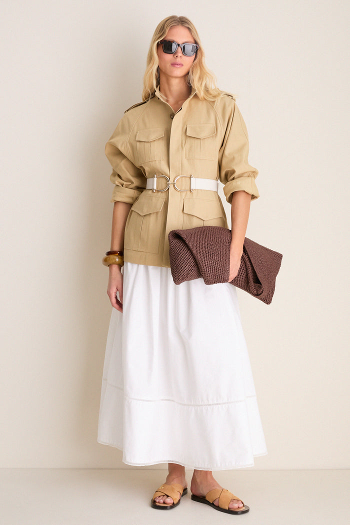 Woman models a classic, high-end look featuring the Gesso Grant Belt with equestrian-style buckles, effortlessly cinching a safari-style jacket over a flowing skirt.