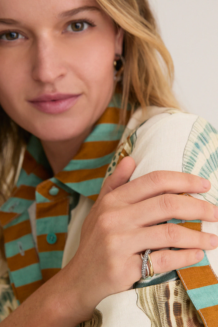 Close-up of a young woman wearing a classic Gold Aya Pinky Ring, exuding an effortless, high-end style with fun, patterned attire and elegant accessories.