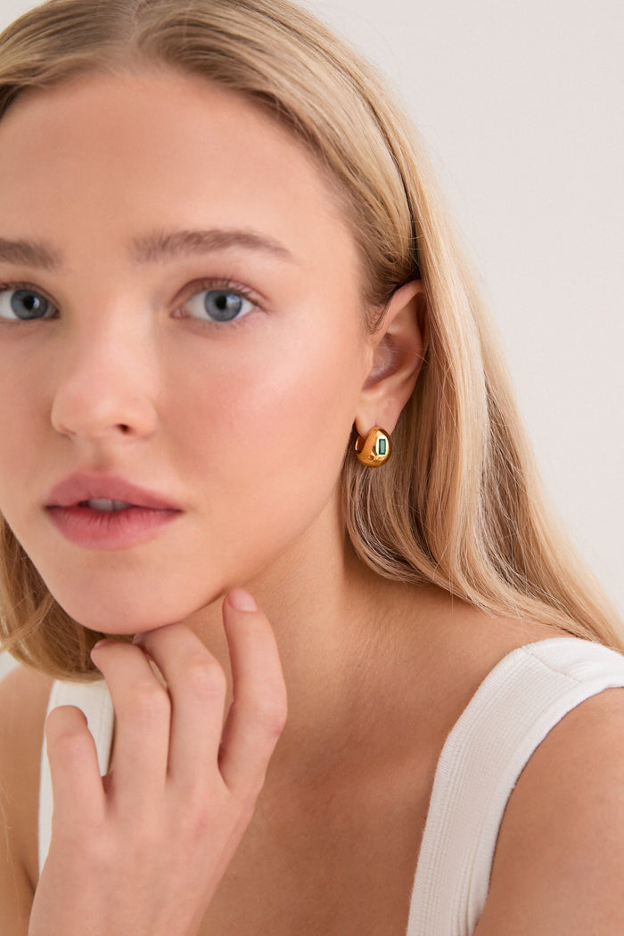 Young woman with classic, high-end Gold Molten Gemstone Baguette Dome Small Hoop Earrings featuring green onyx, embodies effortless elegance and fun sophistication.