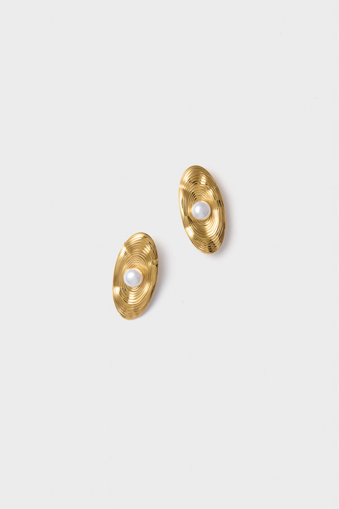 Petit Moments offers textured gold oval stud earrings with concentric ridges and a central white pearl, featuring a modern pearl earring design.