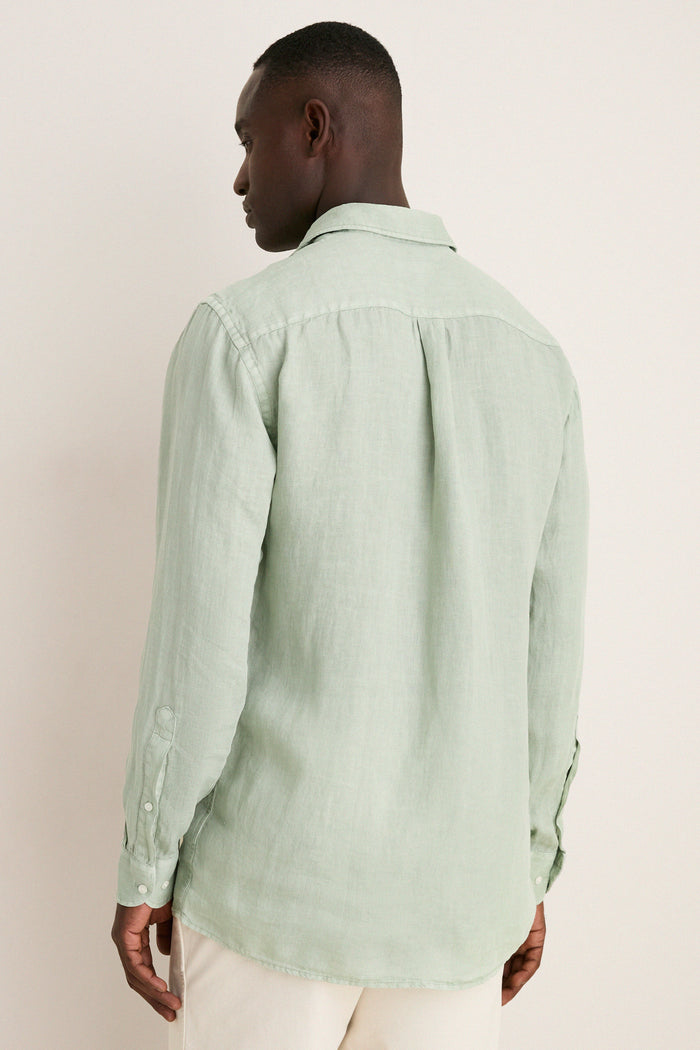 Back view of a man in a classic, light sage-green Grandview Shoreside Linen Sports Shirt, embodying effortless, high-end style with a modern twist.