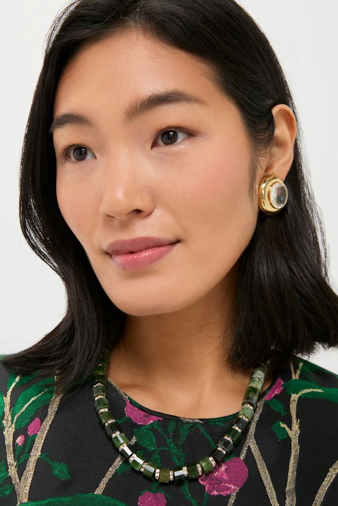Young woman wearing the Green Glimmer Necklace, featuring chunky dark-green beads with metallic spacers, epitomizing an effortless, classic, and high-end style with bold gold earrings.