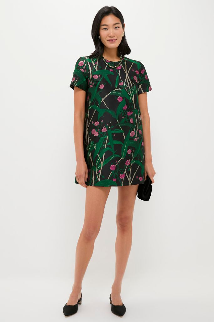 A young woman showcases the classic Green Glimmer Necklace, effortlessly paired with a floral shift dress, embodying a fun and high-end style.