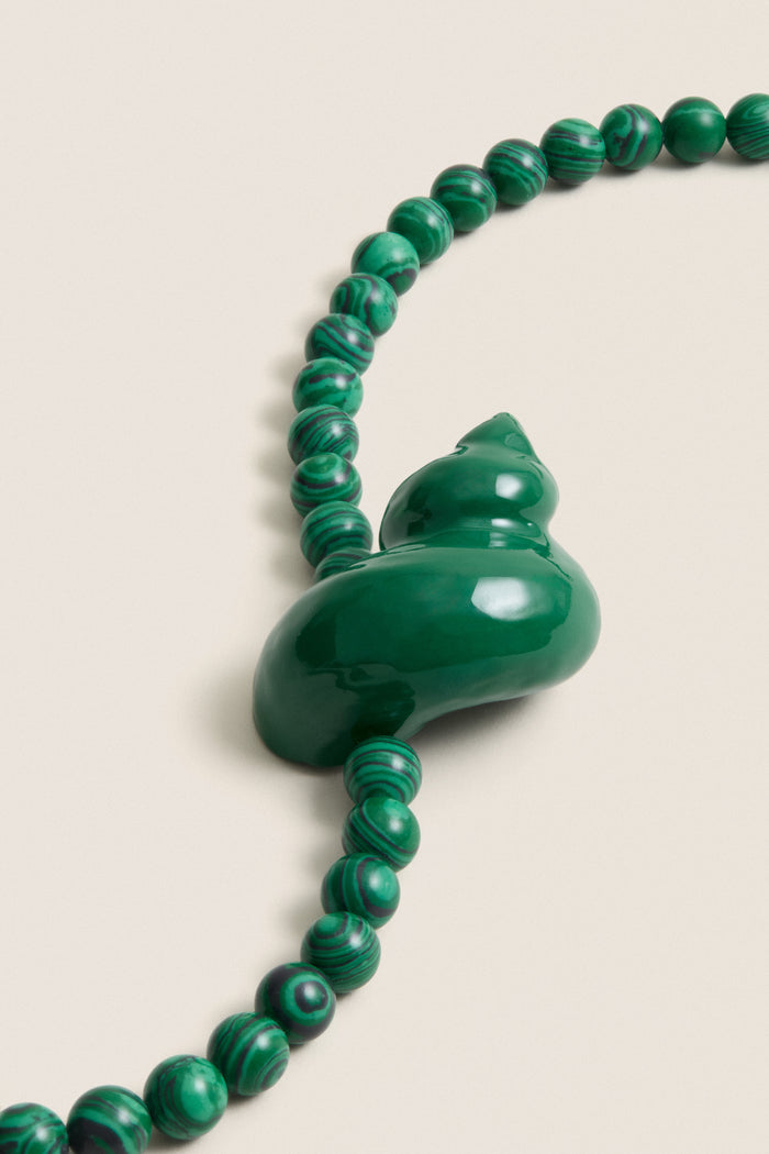 Green Mykonos Necklace featuring classic malachite beads and a sculptural enamel swirl pendant; an effortless, high-end piece perfect for fun, stylish outings.
