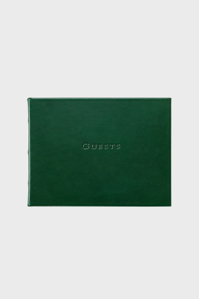 A closed, dark green leather guest book by Graphic Image with "Guests" embossed in uppercase on the front cover.